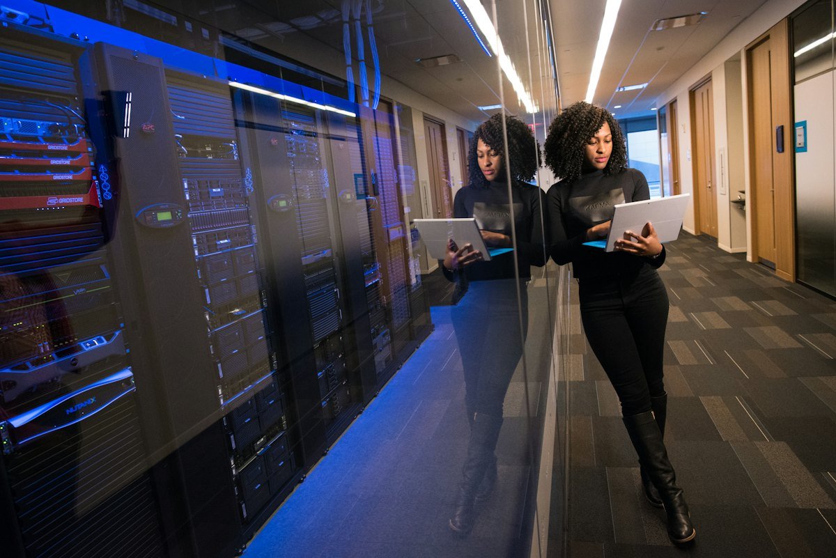 Engineer reviewing a live server environment on a laptop inside a data centre aisle